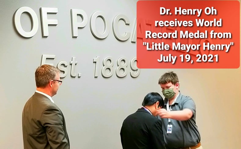 "Little Mayor Henry" awards Dr. Henry Oh with a medal. Mayor Brain stands by.