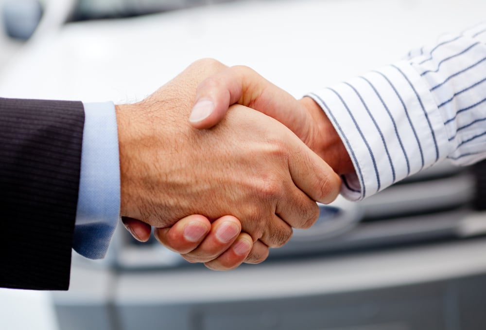 Business handshake to close the deal after buying a car