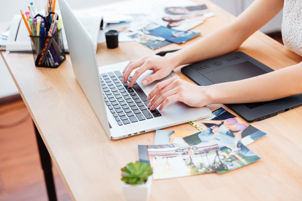 Closeup of hands of young woman photograper typing on laptop keyboard and using graphic tablet-1