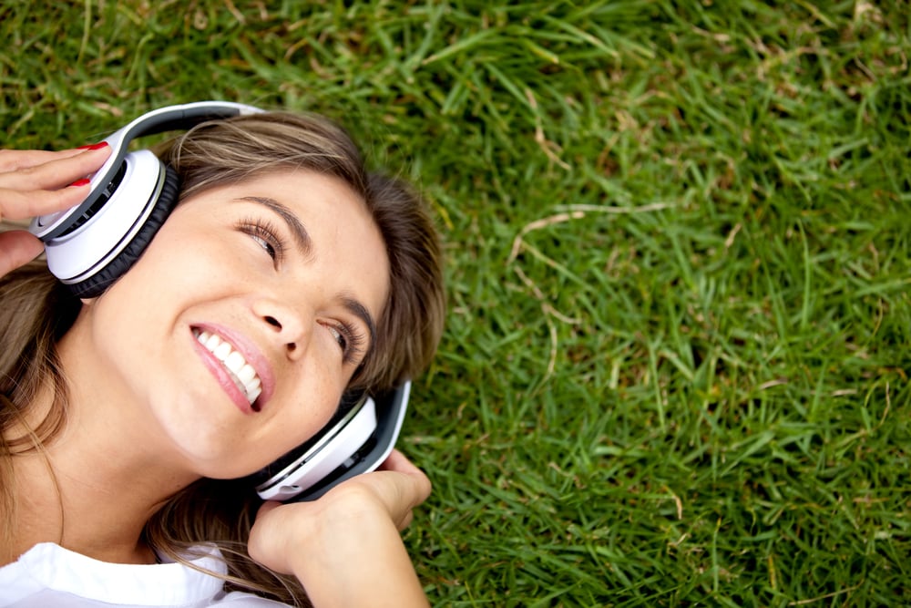 Girl listening to music at the park with headphones