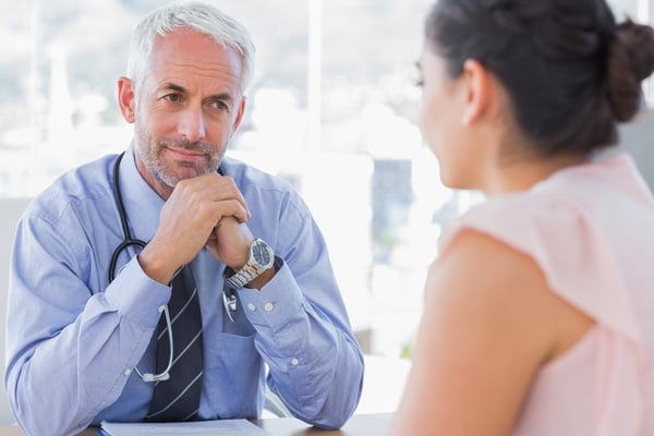 Serious doctor listening to patient explaining her painful in his office