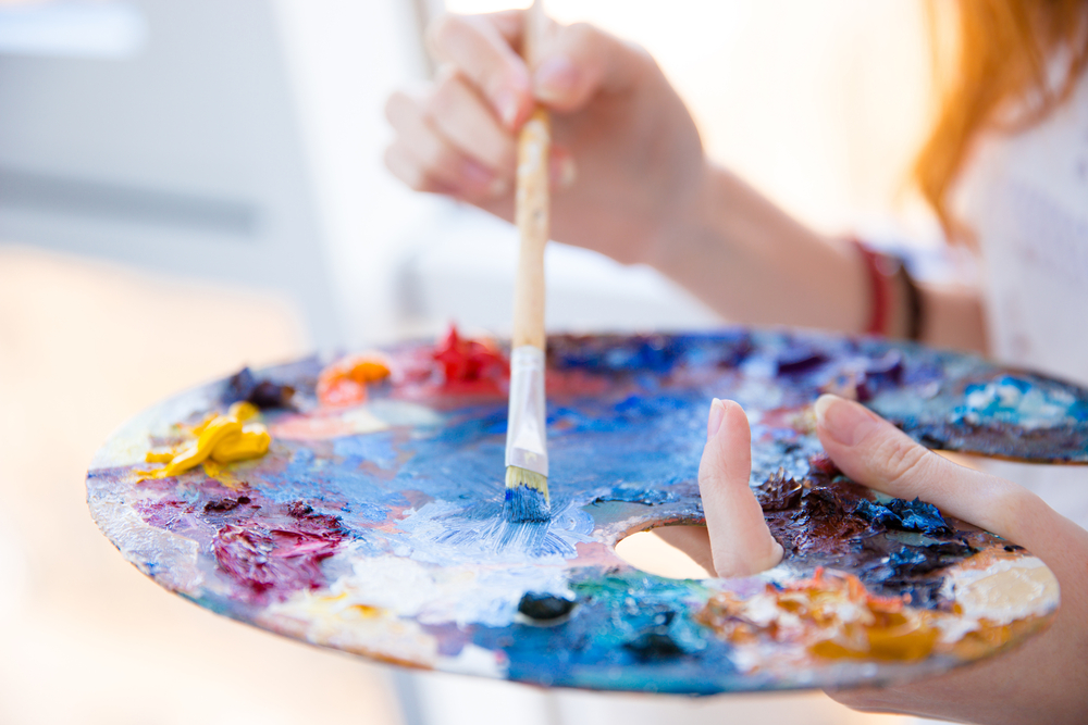 Closeup of paintbrush in woman hands mixing paints on palette-1