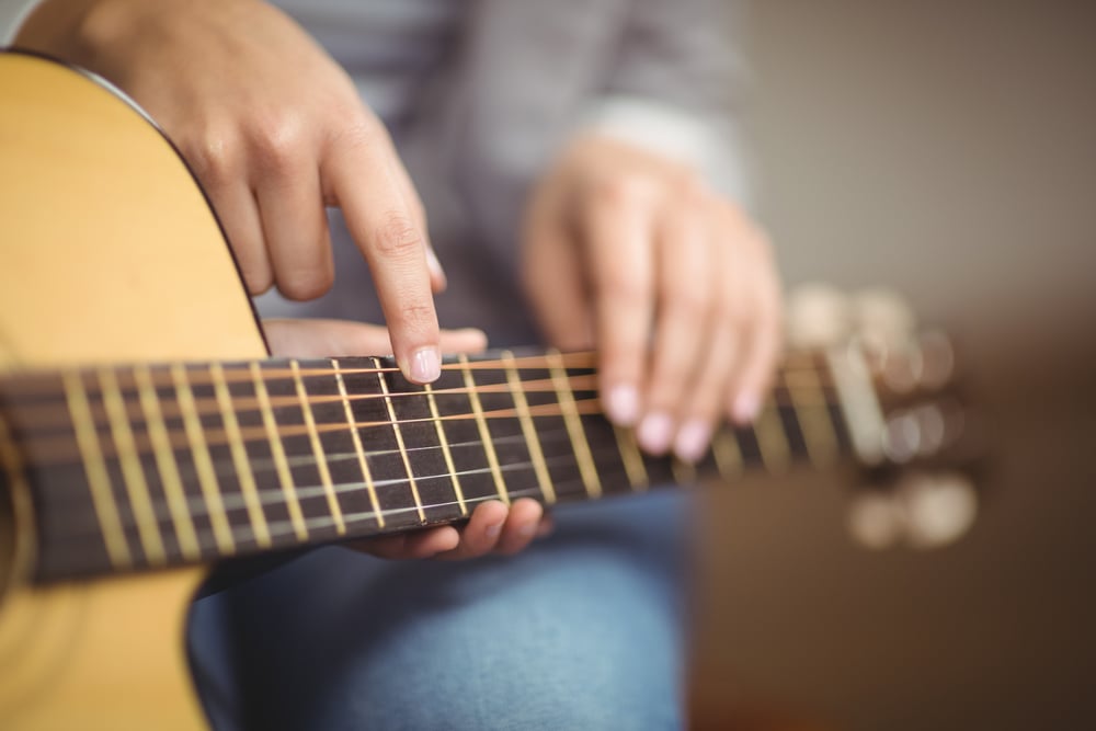 Teacher giving guitar lessons to pupil in a classroom