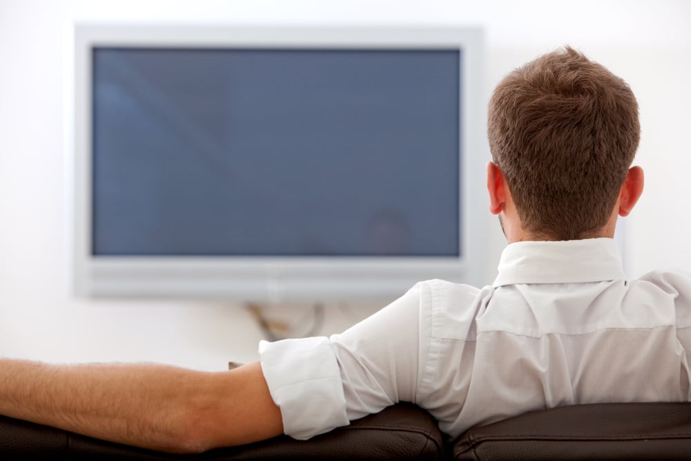 back of man watching tv on a sofa